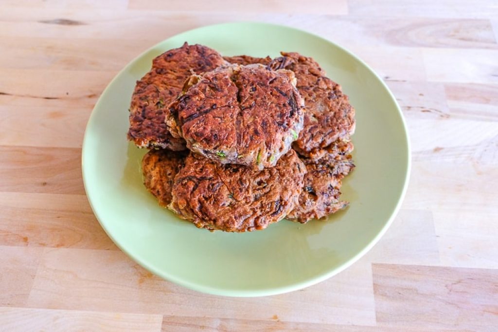 stack of fried bean zucchini fritters on green plate recipe