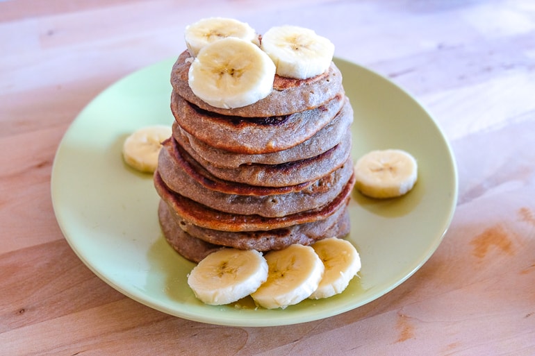 vegan buckwheat banana pancakes in stack on plate with banana slices