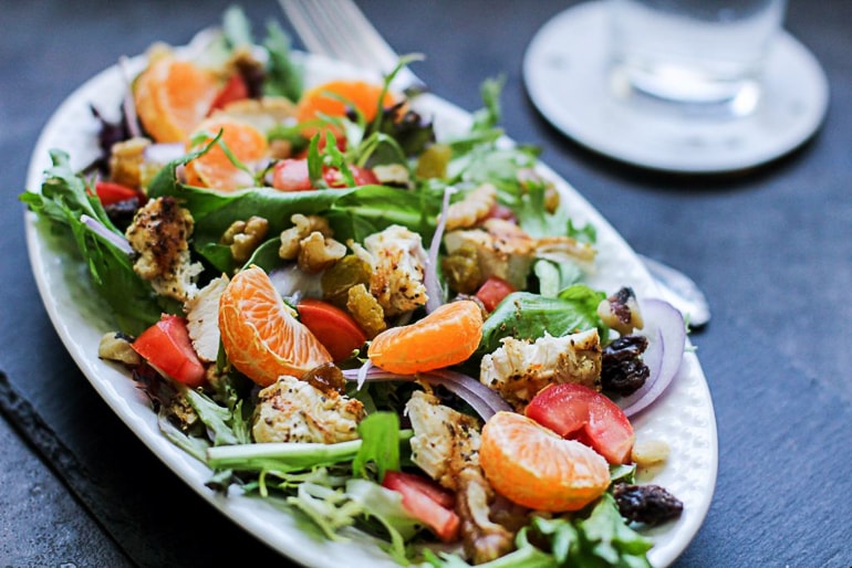 green salad with tangerine on table