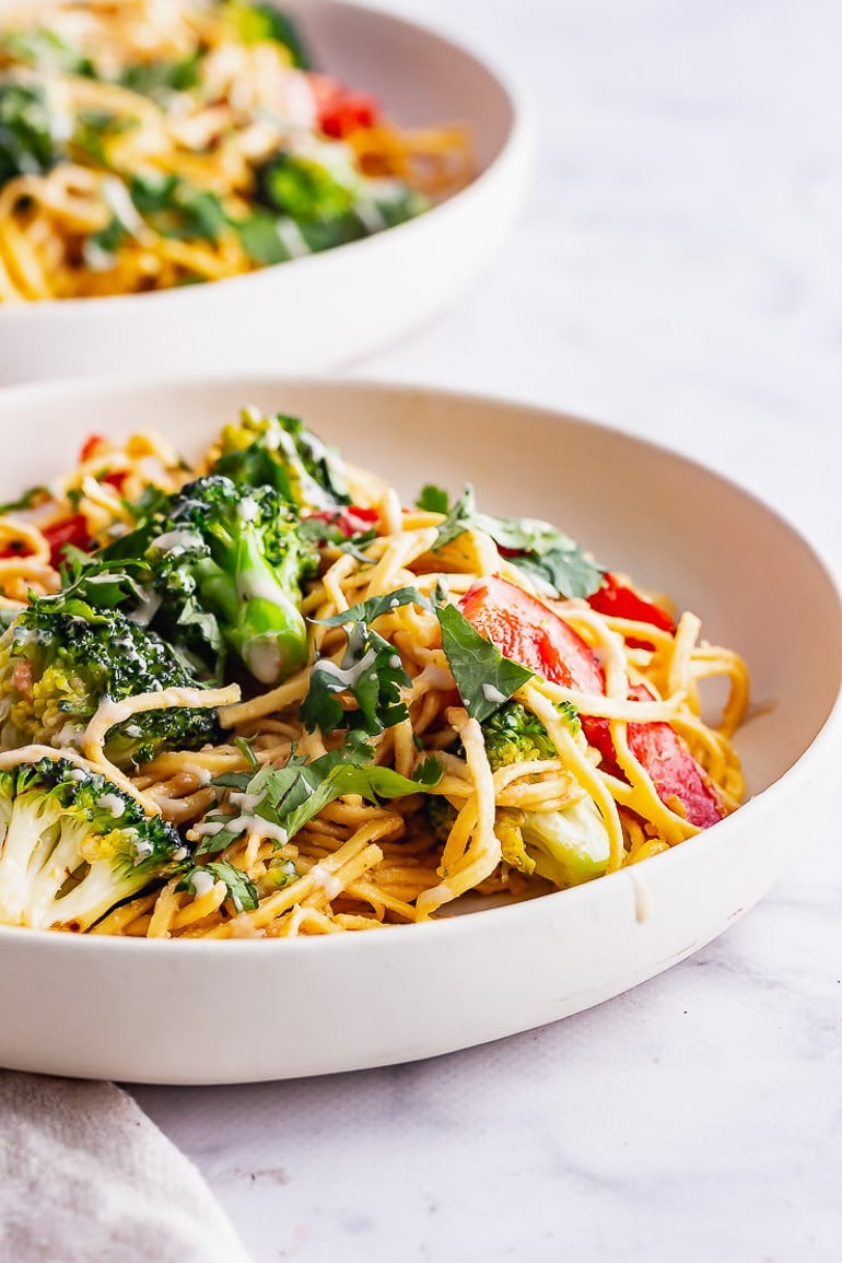 Noodle salad with broccoli and other vegetables in white bowl