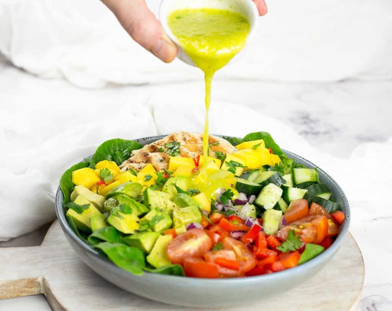 mango salad in bowl with dressing poured over