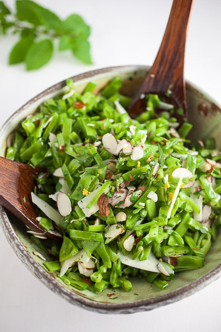 Green pea salad in bowl with wooden spoons
