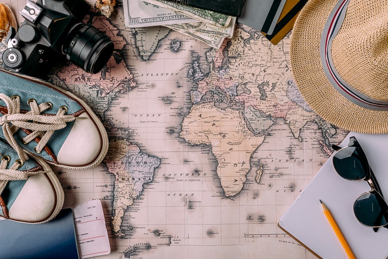 world map laying flat with various travel items around it