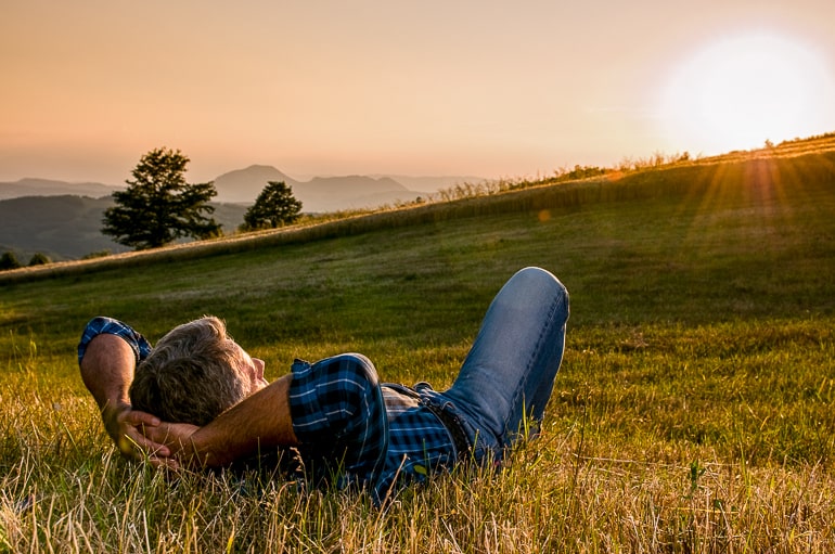 man laying in field looking at sunset introvert alone time