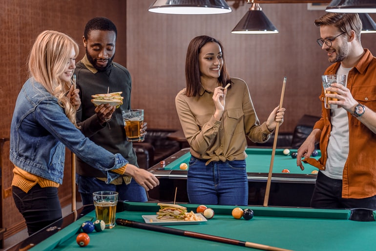 group of friends playing pool behind pool table