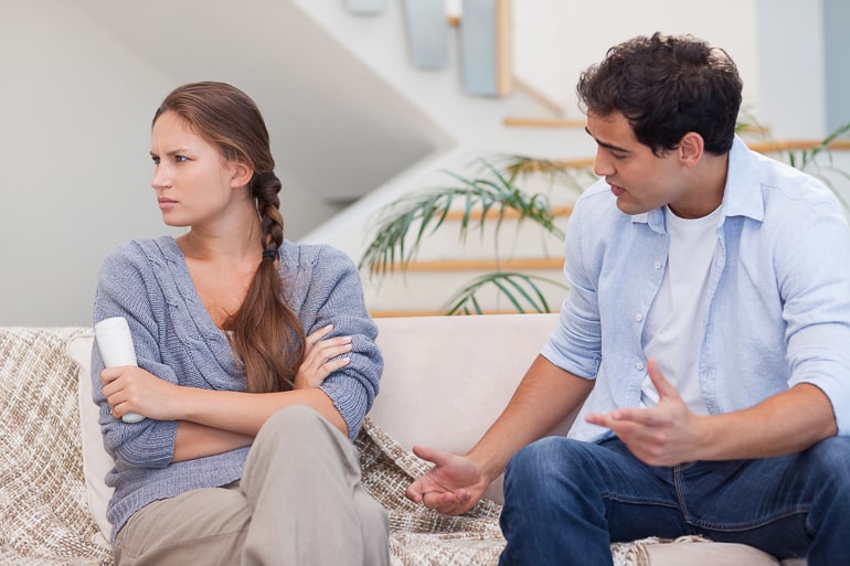 Man and woman sitting on couch with woman looking away from him