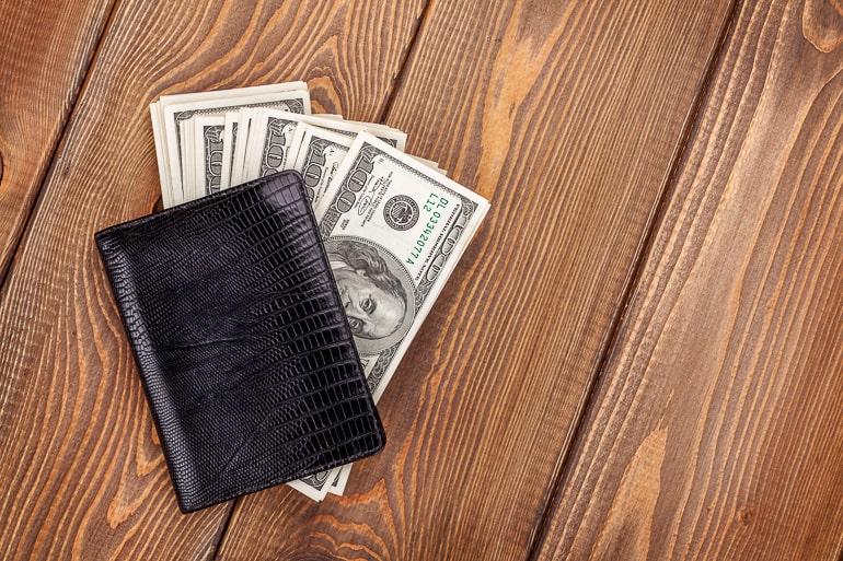 Wallet with money on wooden background