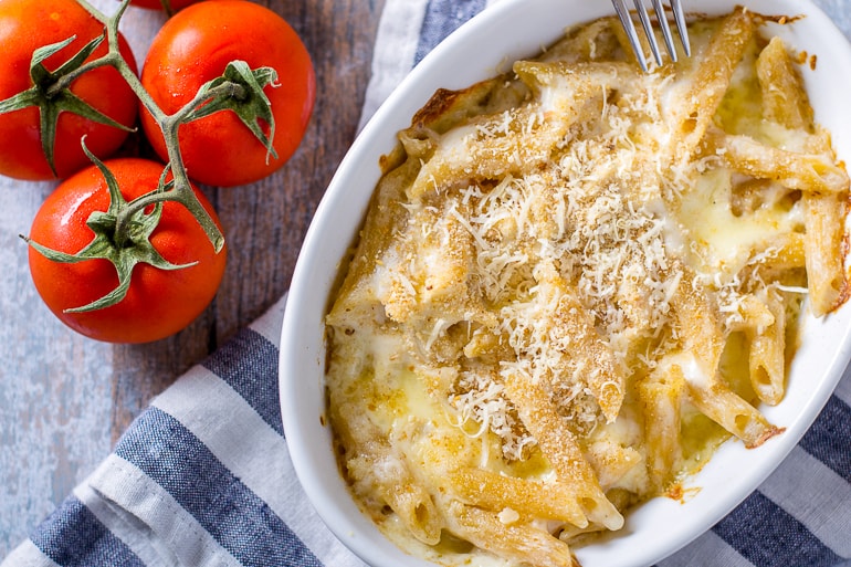 baked dish with cheese on top and tomatoes beside