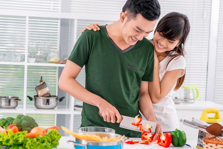 couple cooking together holding knife in kitchen
