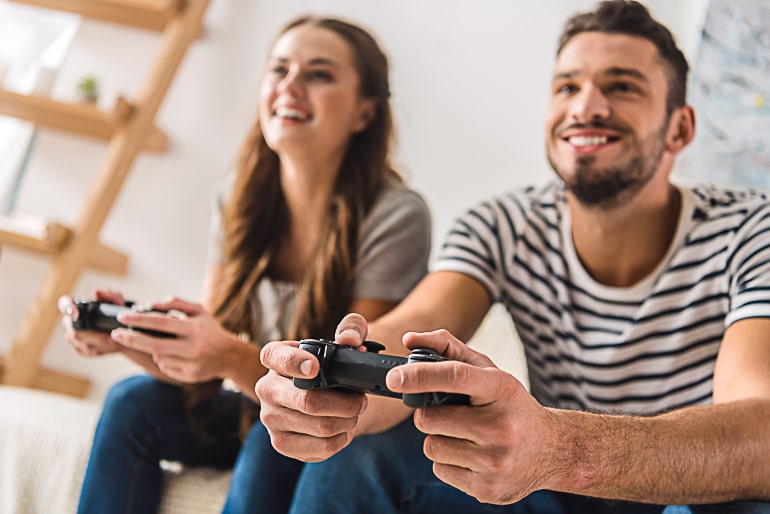 Man and woman sitting on couch holding gaming controllers in their hands