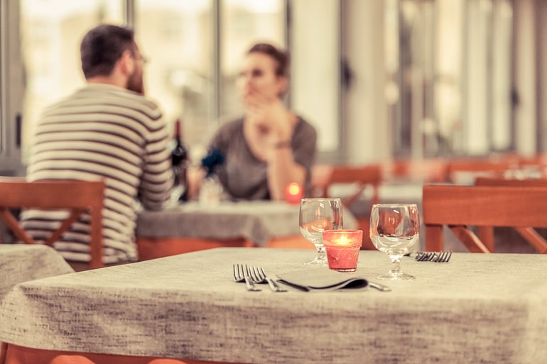man and woman sitting at date table n distance with candle light
