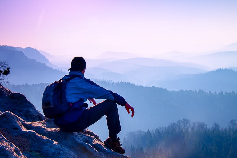 Guy with backpack sitting on rock and staring into distance how to not lose yourself in a relationship