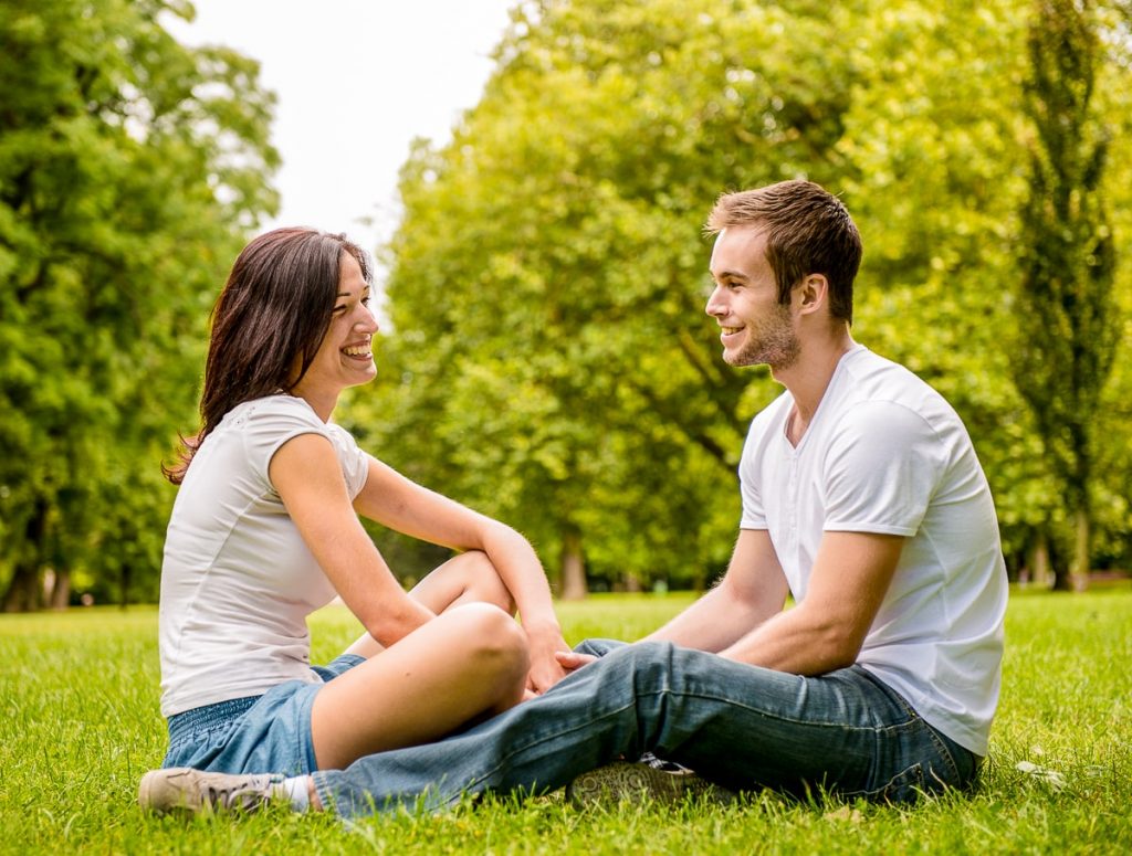 Man and woman sitting in park looking at each other and smiling how to not lose yourself in a relationship