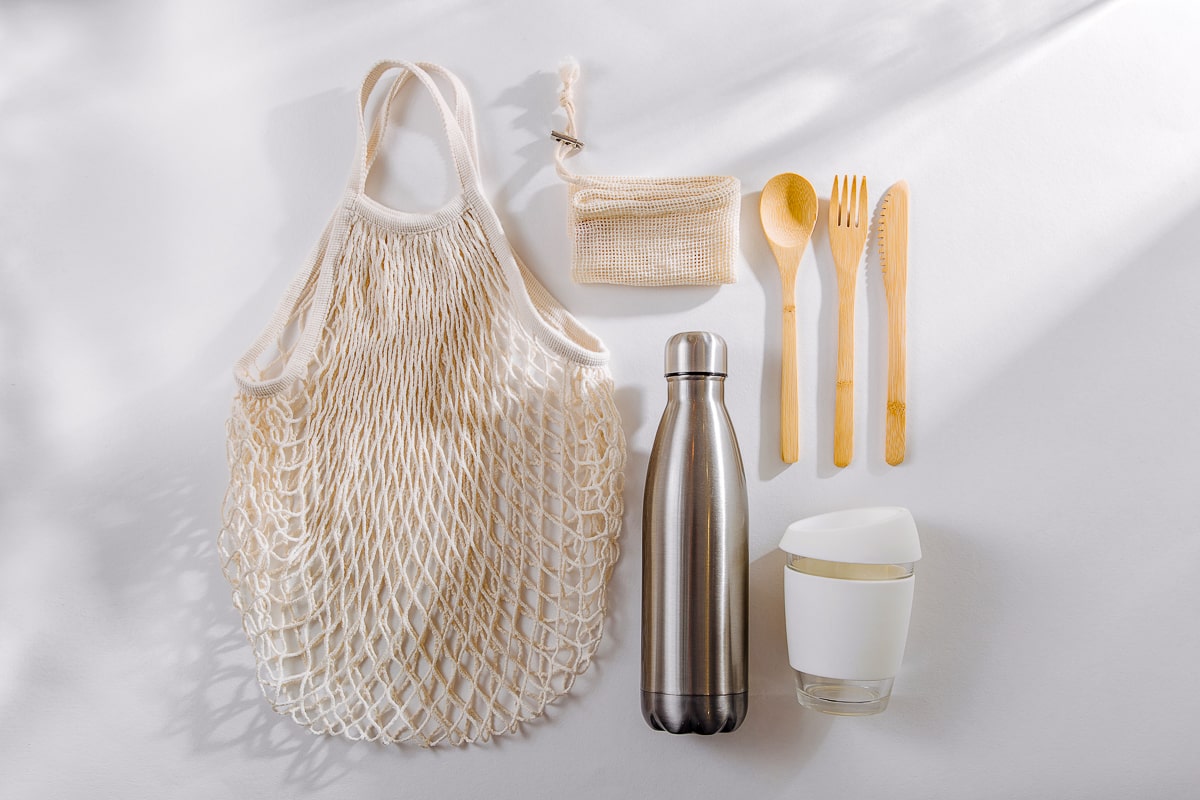 Wooden utensils reusable water bottle coffee mug and grocery bag how to reduce plastic waste at home