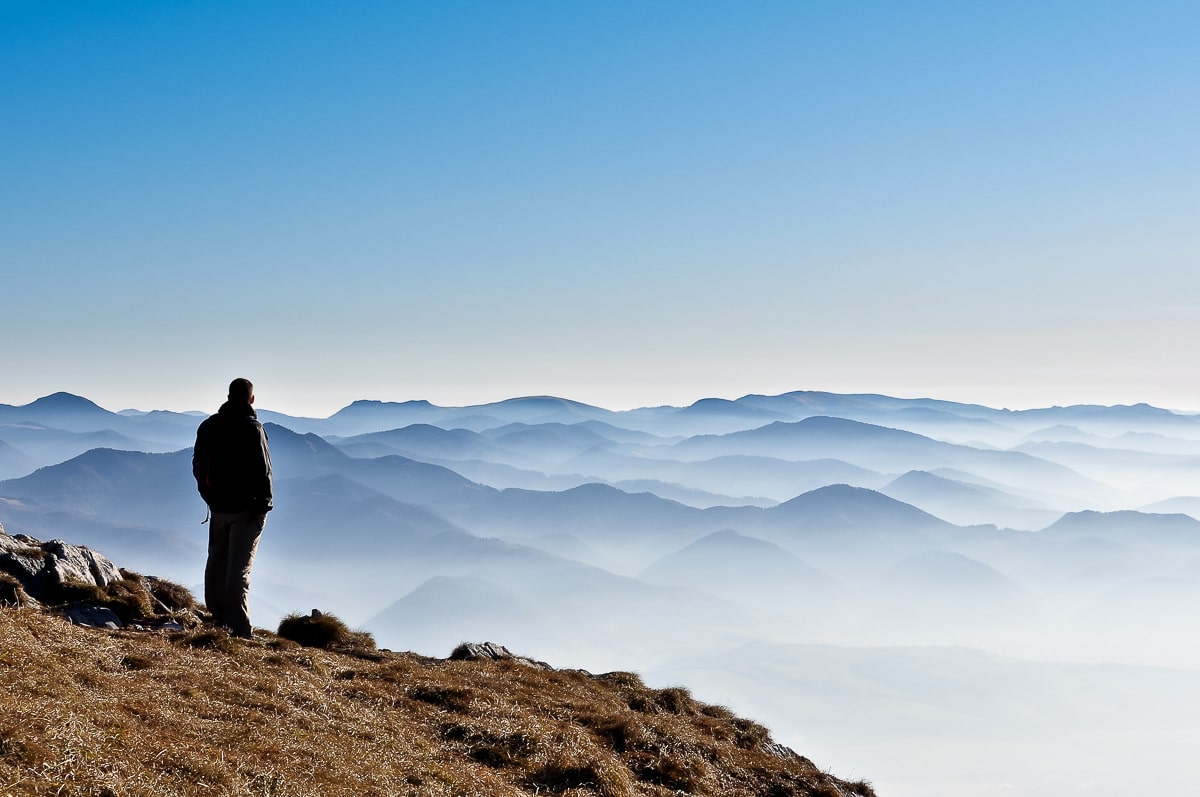 Shadow of man standing on top of mountain with fog and mountains in background how to stop overthinking
