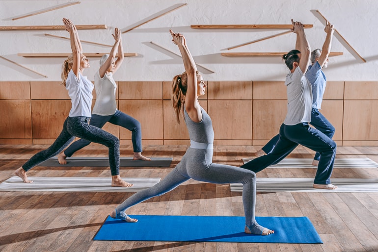 people posing in yoga class with mats underneath importance of yoga in modern life