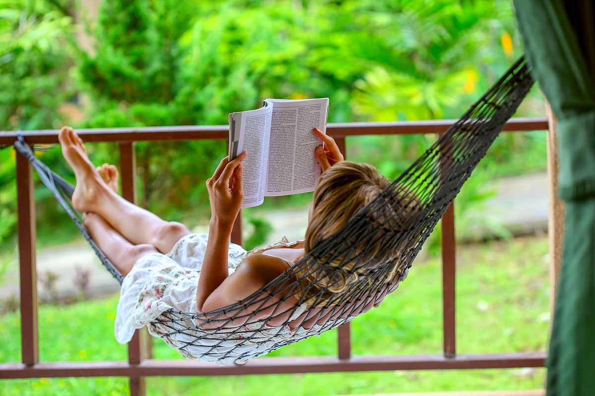 Woman in hammock reading a book with greenery in background self care tips