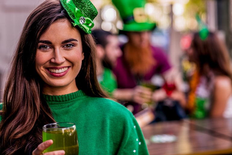 woman wearing green and green hat with st patricks day party behind