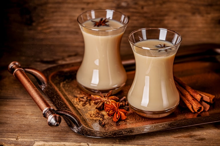 two glasses of chai tea on metal tray