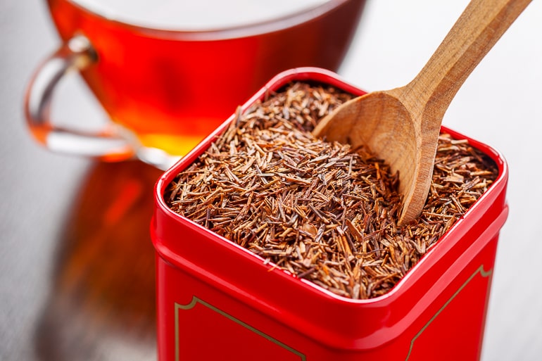 red rooibos tea in red container with wooden spoon tea flavors
