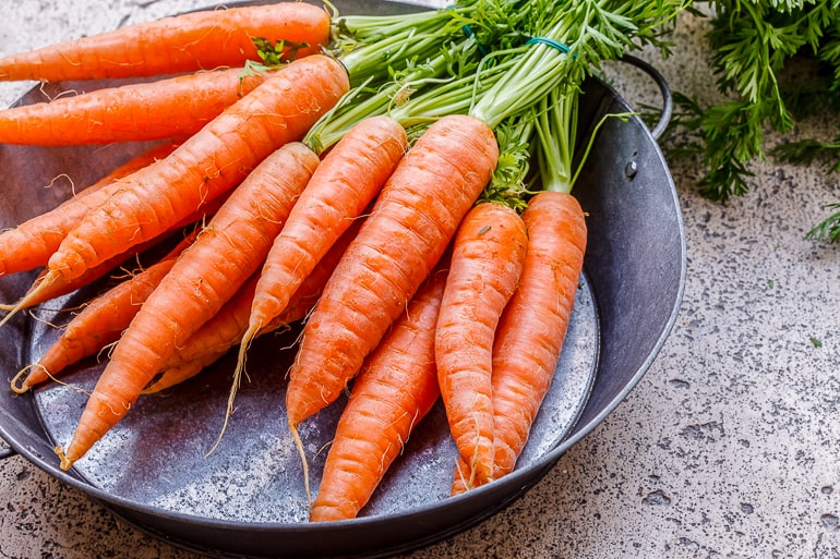 orange carrots with stems on metal plate