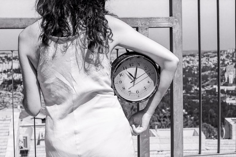 black and white photo of woman holding clock under arm what not to do on a first date