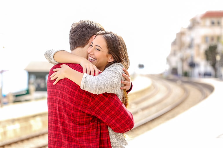 man in red shirt hugging smiling woman with blurry background