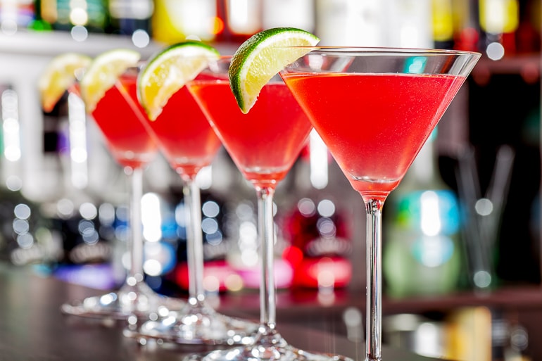 red cosmo drinks in tall wide brimmed glasses on bar top