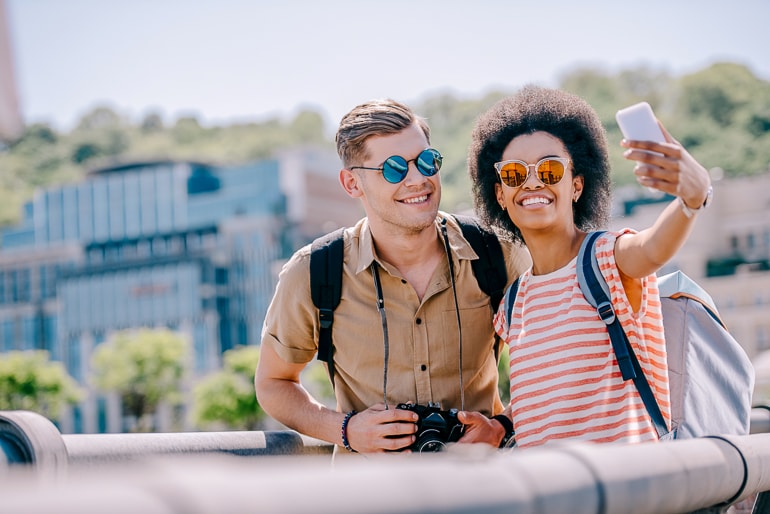 Man and woman with sunglasses and camera taking photo selfie