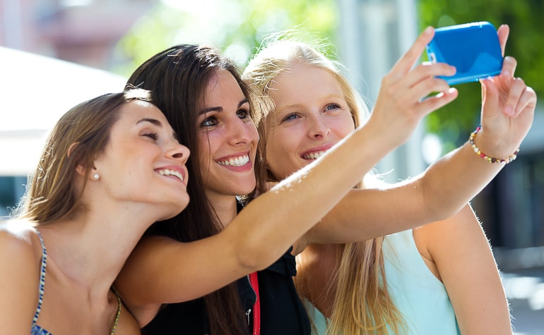 Group of young women taking selfie with blue phone