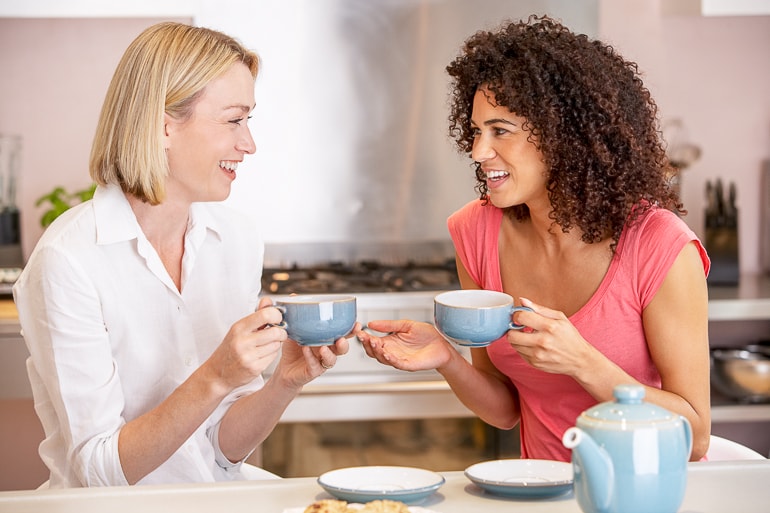 Two woman talking to each other while holding blue mugs