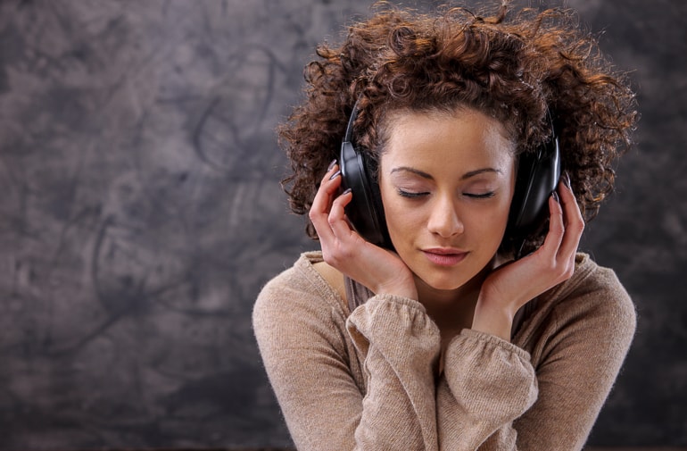 Woman having eyes closed while wearing dark headphones