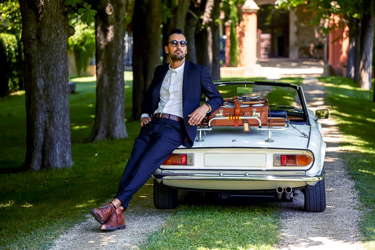 Man in suit leaning against vintage car with trees in background instagram captions men