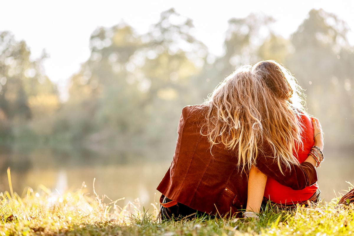 Backs of two girls sitting on grass and hugging each other picture captions for girls
