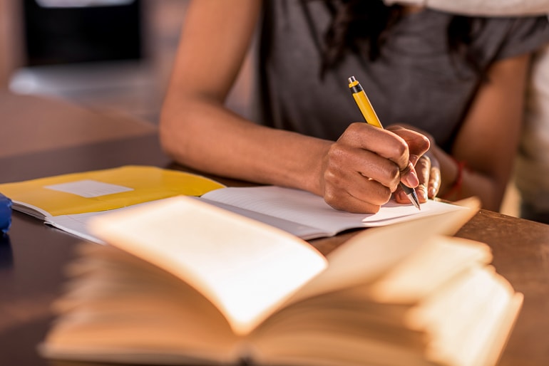woman writing in book with pencil on desk inner writer tips