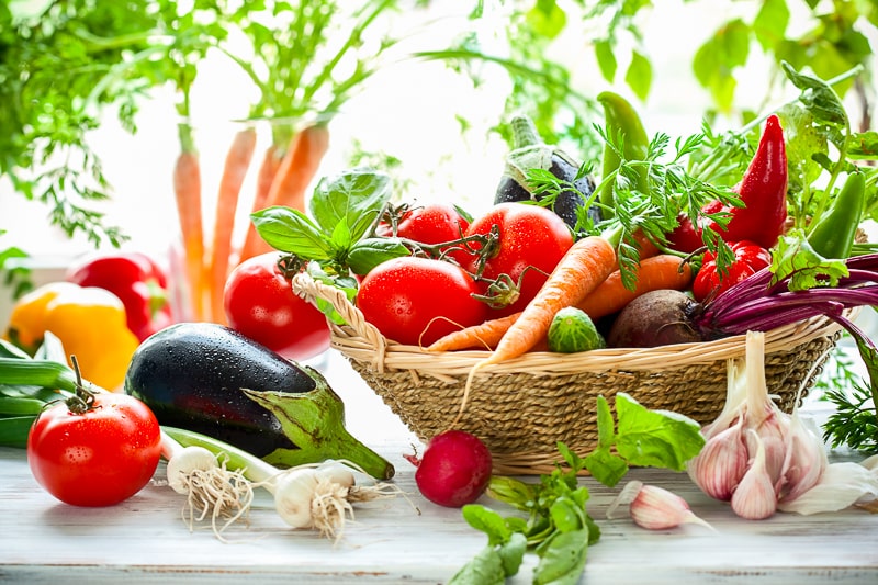 assorted fresh vegetables in basket on white counter saving money on groceries