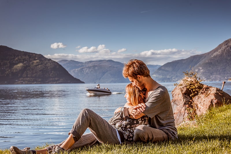 couple laying on grass beside lake with boat behind how to stop fighting in a relationship