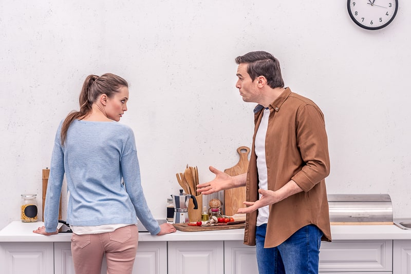 man and woman standing in kitchen arguing in relationship