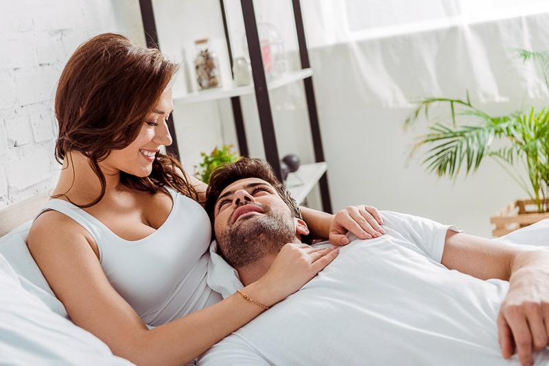 man and woman cuddling in white bed