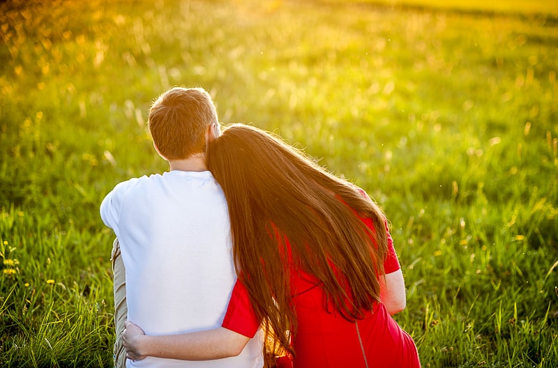 man and woman wearing red dress sitting on green grass how to strengthen your relationship 