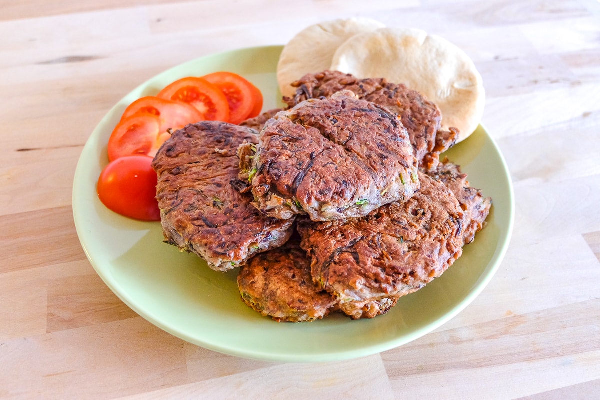 plate of bean zucchini fritters recipe with tomato and pita