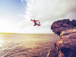 man jumping off cliff into water being a yes person