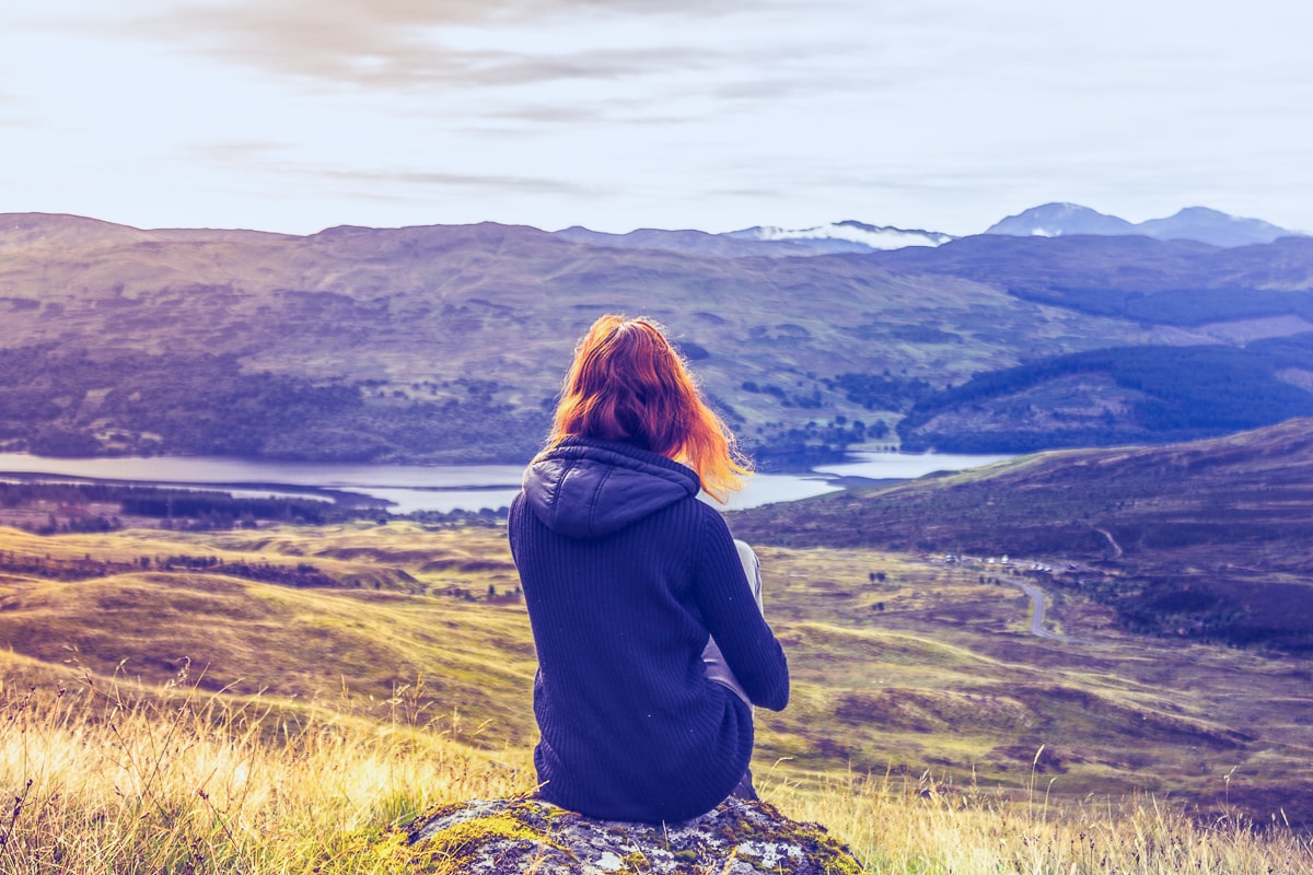 woman sitting in rock with valley below best free meditation apps