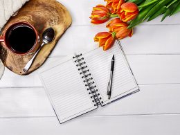 Open Journal with pen flowers and coffee mug on white background gifts for people with anxiety