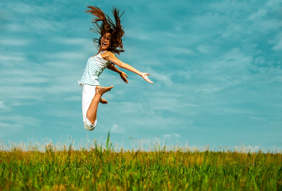 Woman jumping in air with green grass and blue sky how to be successful in life