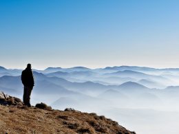 Shadow of man standing on top of mountain with fog and mountains in background how to stop overthinking