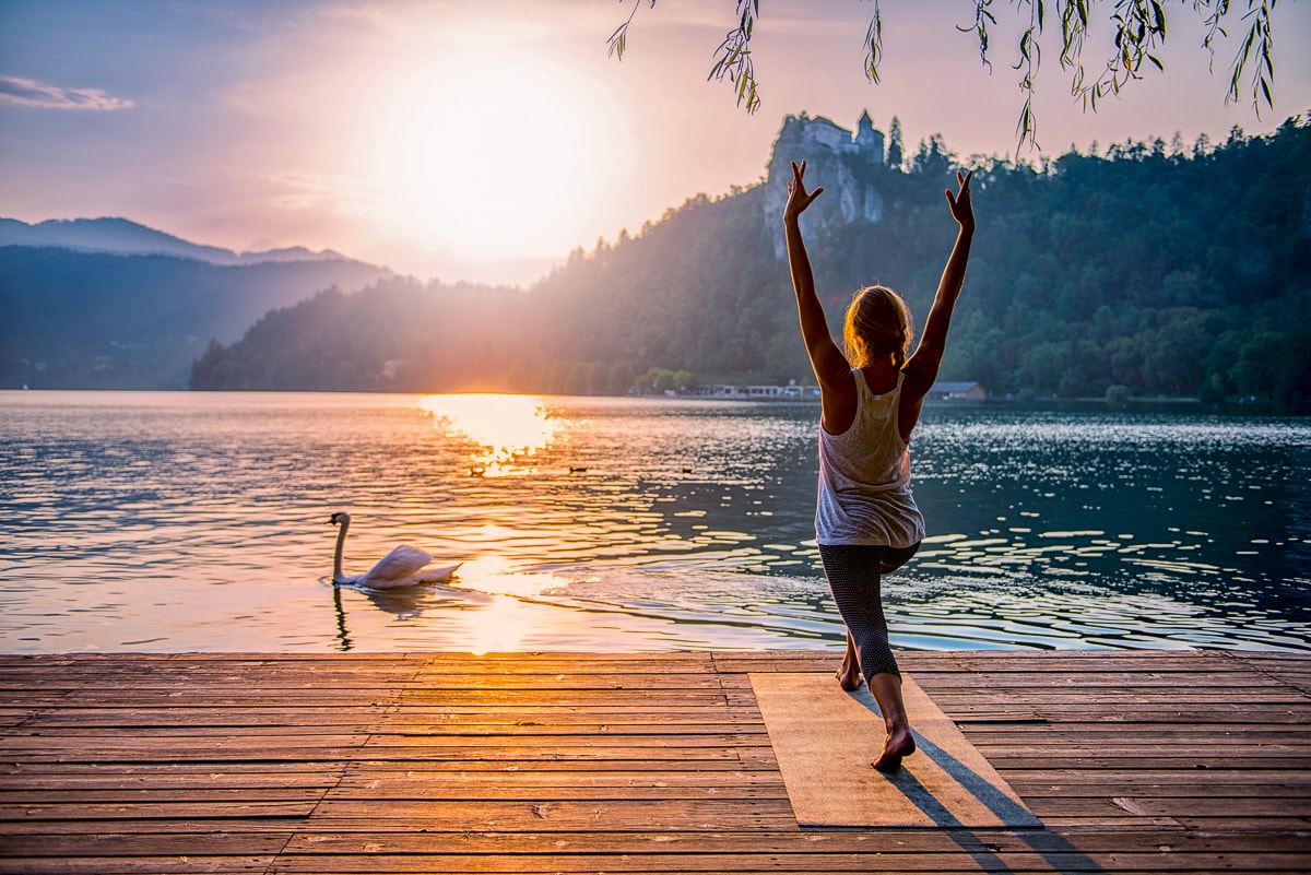 woman on yoga mat on dock with sunrise in front