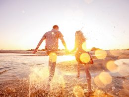 couple running along beach in water with sun shining live in the moment quotes